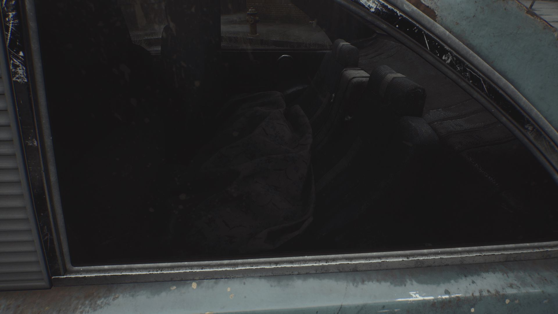 A dark, abandoned car interior viewed through a dusty window, with a shadowy, indistinct object on the back seat.