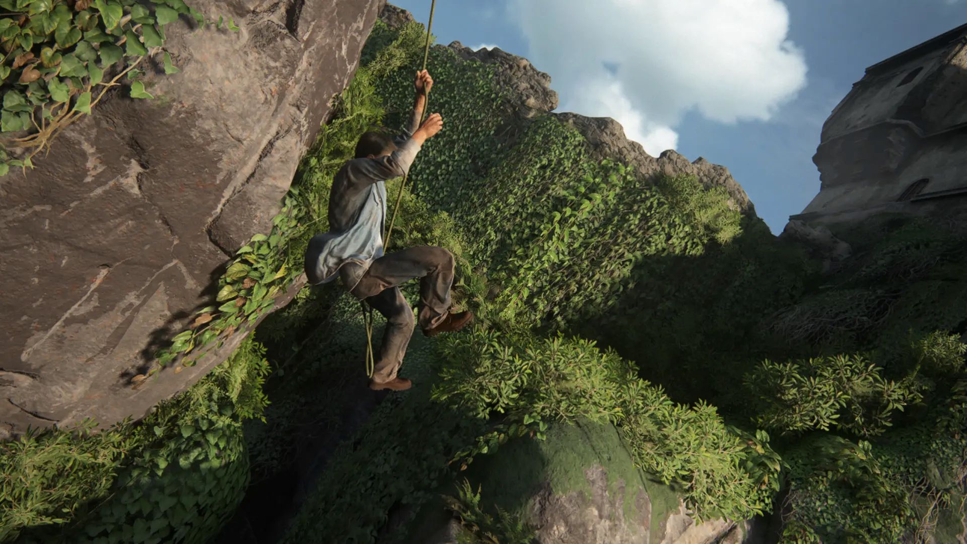 A man climbs a rope between steep cliffs covered in lush green vegetation, with a tall stone structure visible at the top right.