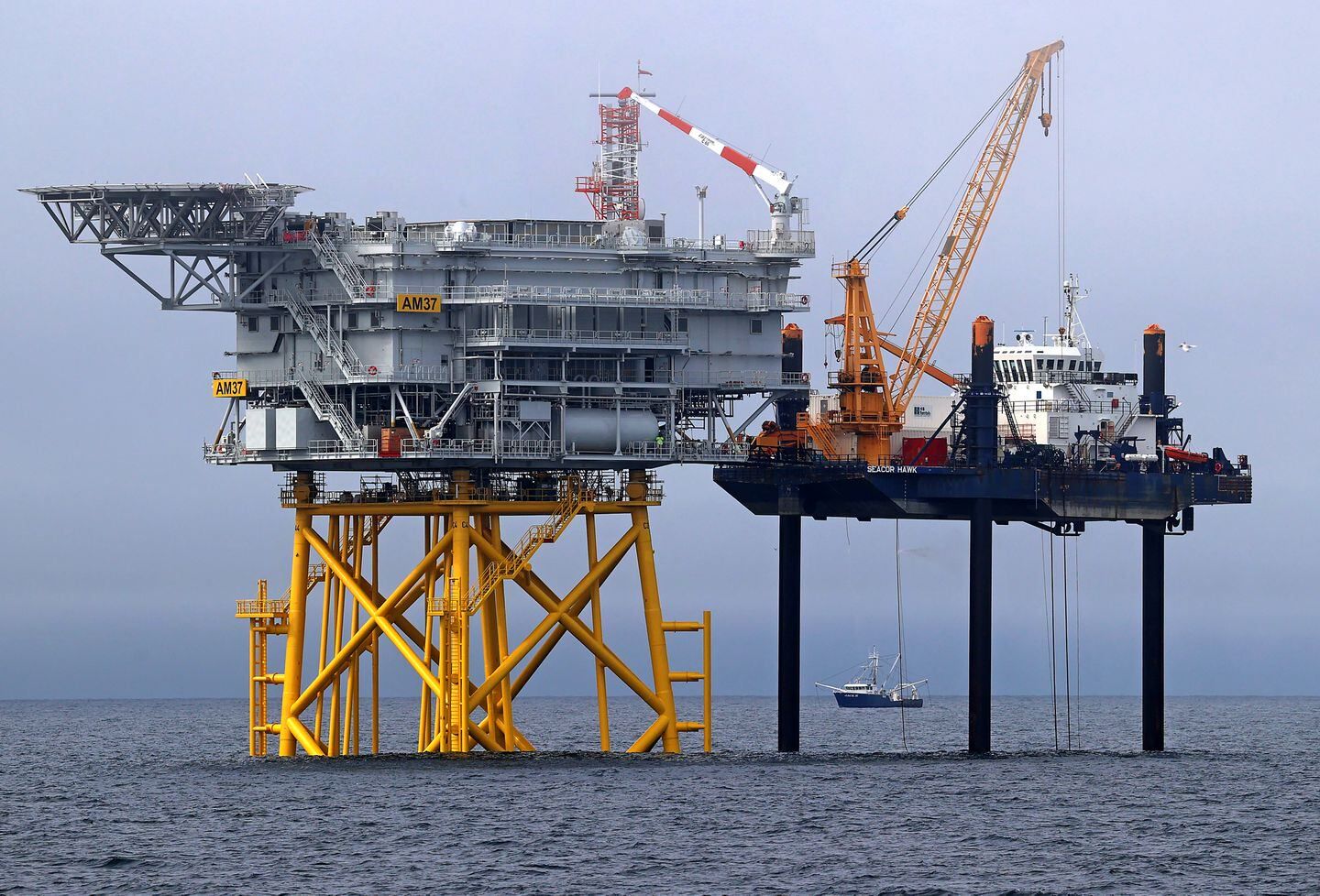 An offshore sub station and the wind turbine installation lift boat SEACOR Hawk on legs that go down to the sea bed floor.